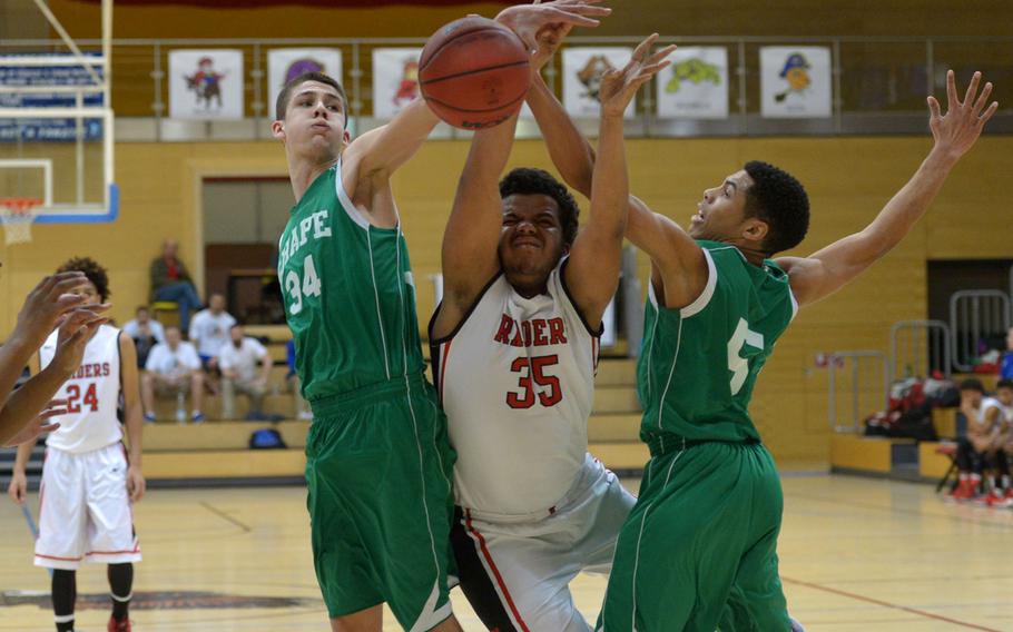 Kaiserslautern's Robert Brown is fouled as he tries to drive between SHAPE's Zackery Reed, left, and Michael Majors in a Division I semifinal at the DODDS-Europe basketball championships in WIesbaden, Germany. Friday, Feb. 26, 2016. Kaiserslautern beat SHAPE 42-27 to advance to Saturday's final against Ramstein.