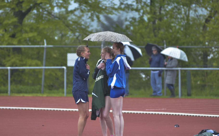 Athletes huddle under umbrellas during an 11-team meet at Wiesbaden, Saturday, April 23, 2016. Especially early on, the meet was marked by precipitation and cold, windy weather.