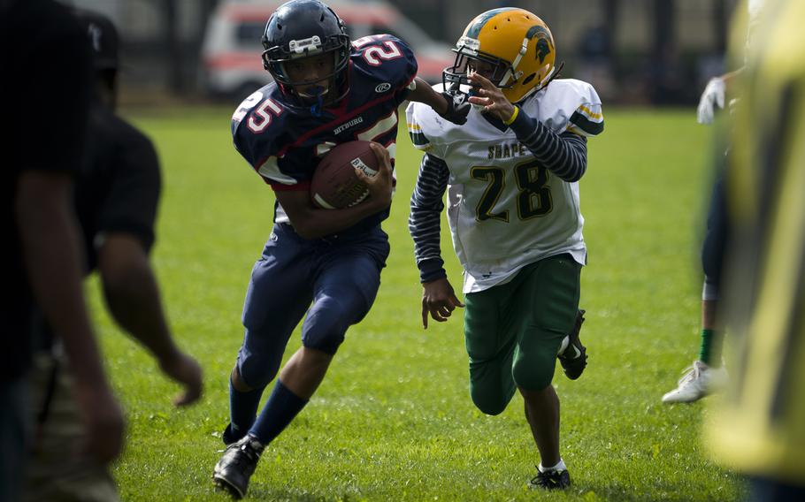 Bitburg Baron Deon Montgomery runs past SHAPE Spartan Hiran Mingo in Bitburg, Germany, on Saturday, Sept. 17, 2016. The Barons won the game 44-3.