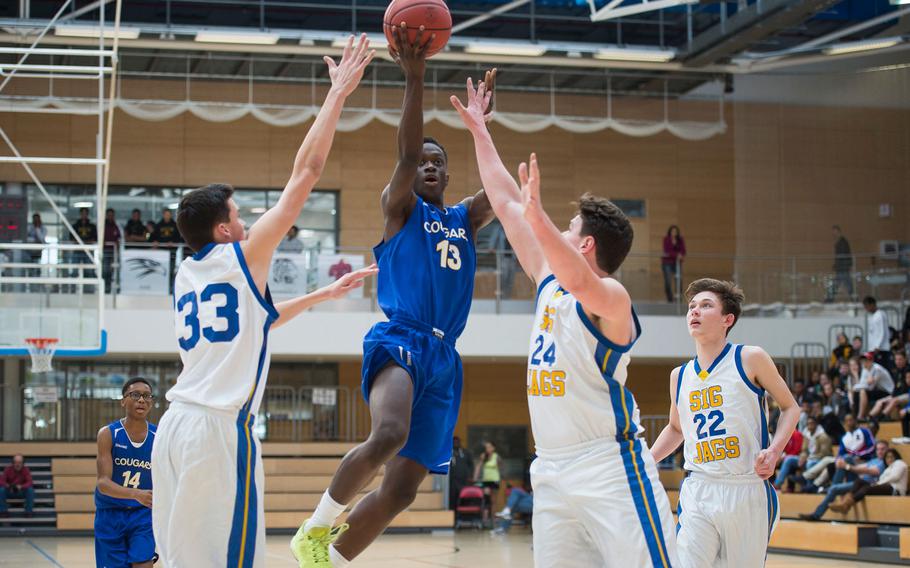 Ansbach's Kevin Kamara goes up for a layup over Sigonella's Isaac Griswold, left, and Alex Ogletree during the DODEA-Europe Division III championship in Wiesbaden, Germany, on Saturday, Feb. 25, 2017. Ansbach lost 32-31.