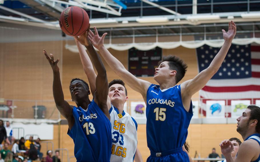 Ansbach's Nick Benson, right, Kevin Kamara and Sigonella's Isaac Griswold jump for a rebound during the DODEA-Europe Division III championship in Wiesbaden, Germany, on Saturday, Feb. 25, 2017.