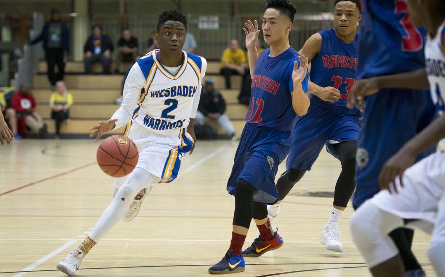 Wiesbaden's Donte Hurt, left, dribbles past Ramstein's Nicholas Bautista during the DODEA-Europe Division I championship in Wiesbaden, Germany, on Saturday, Feb. 25, 2017. Wiesbaden lost the game 48-46.