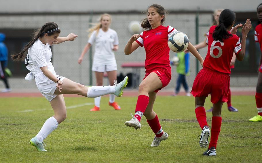 Ramstein's Kelsey Mashburn takes a shot through International School of Brussels' Tasneem Amijee, far right, and Daniela van den Brink at Ramstein Air Base, Germany, on Friday, April 28, 2017. Ramstein won the game 4-1.