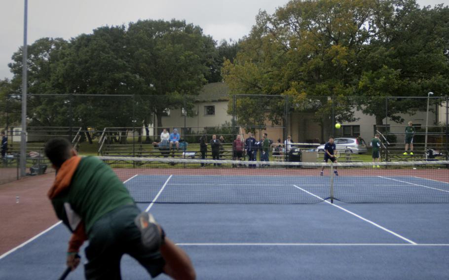 SHAPE Spartan Luis Eliza delivers a fast serve against Lancer Joshua Choi during a singles tennis match in slight rain at RAF Lakenheath, England, Friday, September 15, 2017. Eliza earned a 6-2 victory.