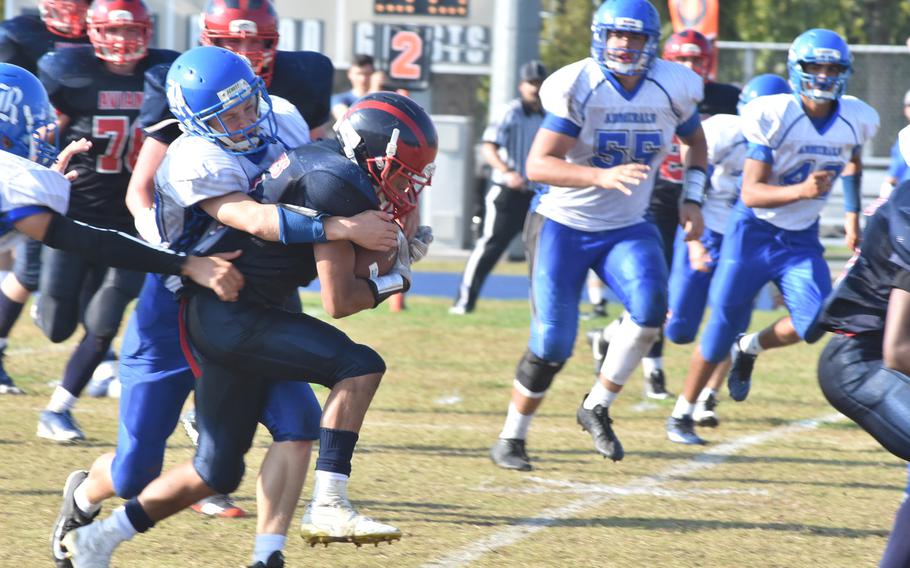 Aviano's Mickey Moore carries Rota's Kaleb Helvey for a few yards Saturday in the Saints' 33-30 victory over the Admirals.