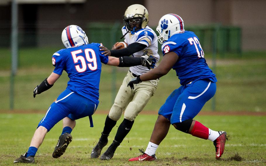Wiesbaden's Caleb Brown tries to get through Ramstein's Kyle Lloyd, left, and Clifford Jackson during the DODEA-Europe Division I semifinal at Ramstein Air Base, Germany, on Saturday, Oct. 28, 2017.