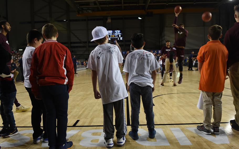 Young basketball fans watch the Texas Aggies finish warming up before playing West Virginia during the Armed Forces Classic at Ramstein Air Base, Germany, on Friday, Nov. 10, 2017.