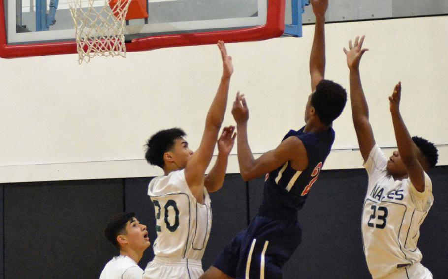 Lakenheath’s Michael Lacy shoots against two Naples defenders during a varsity basketball game at RAF Lakenheath, England, Saturday, December 2, 2017. The Lancers beat the Wildcats 58-50. 