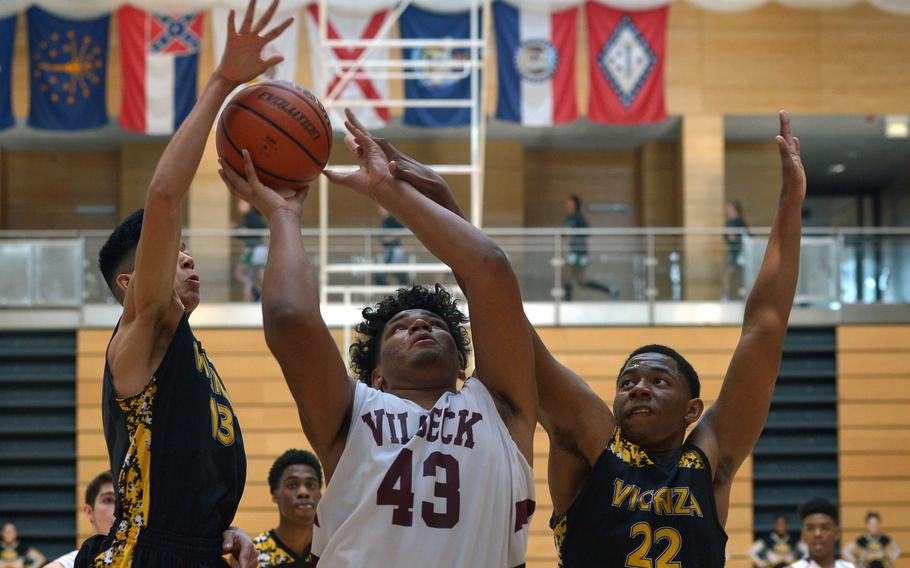 Vilseck's Jonas Matthews takes a shot against the Vicenza defense of Angel Graulau, left, and Kai're Grant in a Division I game at the DODEA-Europe basketball championships in Wiesbaden, Germany, Wednesday, Feb. 21, 2018. Vilseck won the game 54-28.