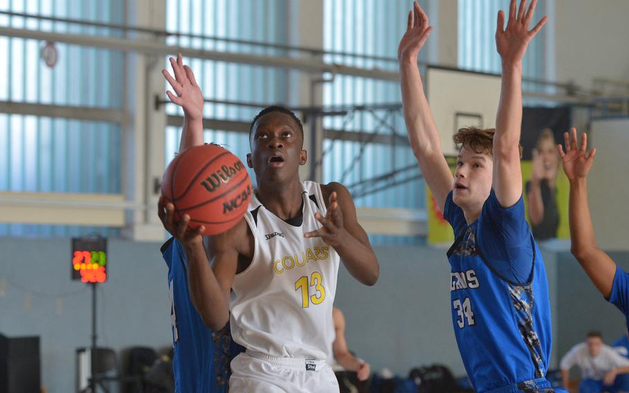 Ansbach's Kevin Kamara aims for the basket after getting past Brussels' Callum Proulx, left, and Alex Crowson in a Division III game at the DODEA-Europe basketball finals in Wiesbaden, Germany, Thursday, Feb. 22, 2018.