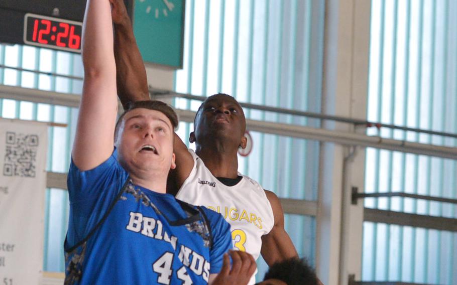 Brussels' Callum Proulx takes a shot under pressure from Ansbach's Kevin Kamara, center, and Ogden Andrew in a Division III game at the DODEA-Europe basketball finals in Wiesbaden, Germany, Thursday, Feb. 22, 2018.