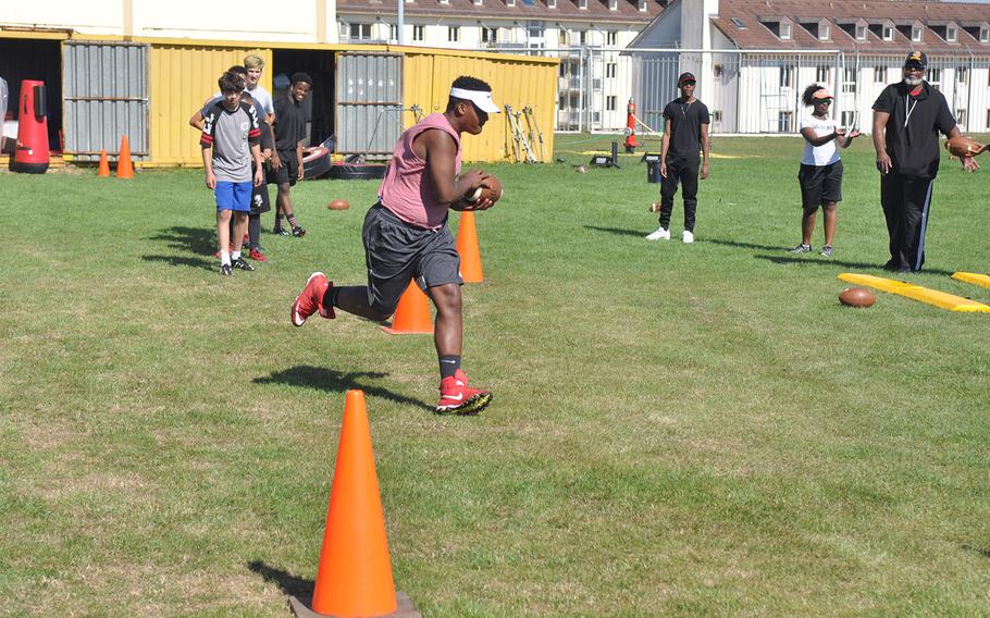 Baumholder senior Jeremiah Christopher catches a pass from head coach Phillip Loyd in a preseason football drill. The all-conference lineman will face a major adjustment as the Bucs convert from 11-man to six-man football this fall. 