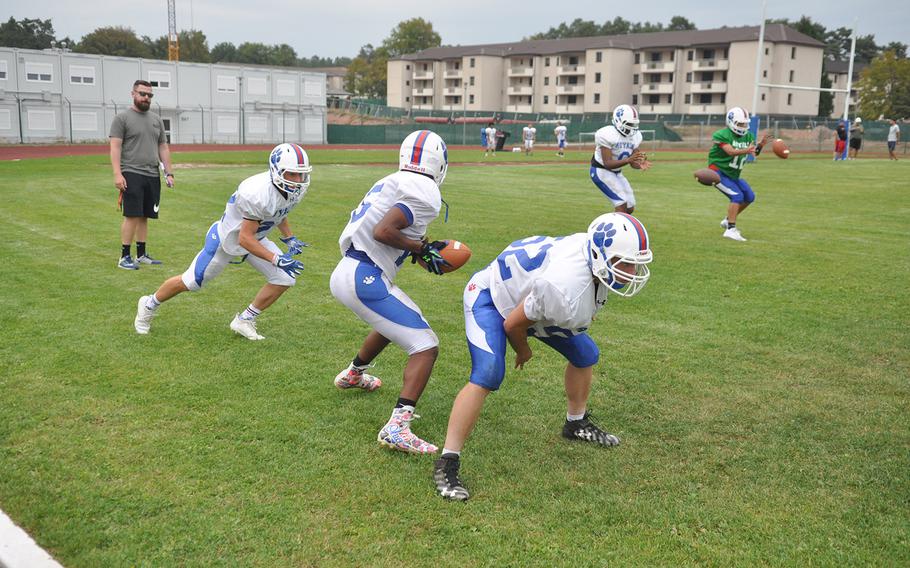 Ramstein's JJ Little takes a snap from Marcus Bradley and prepares to hand off to Oliver Seelig in an offensive drill at Ramstein Air Base, Germany. The Royals have several key offensive players back from last year's European runner-up. 