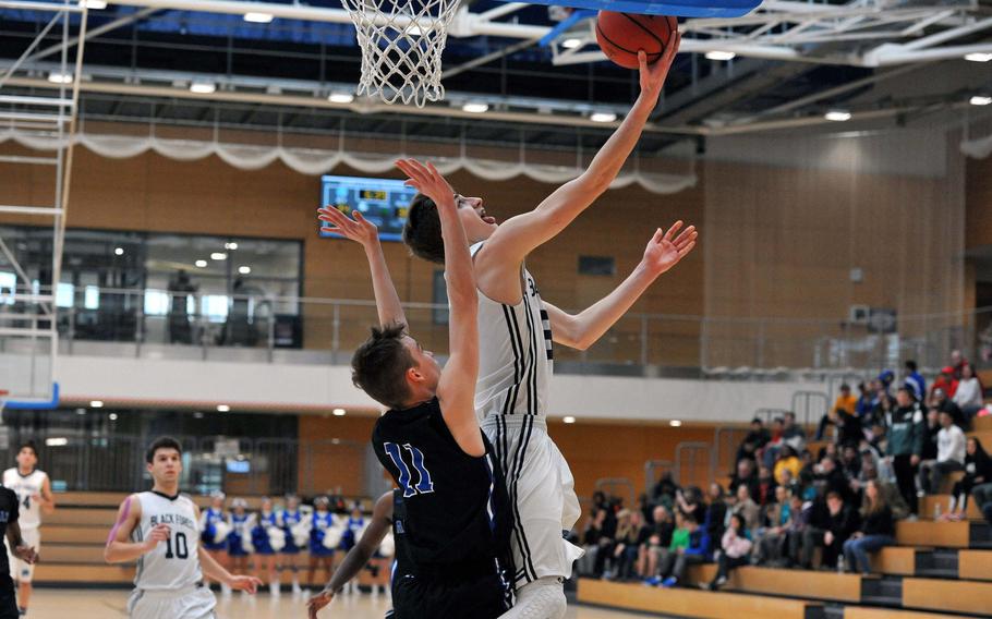 Black Forest Academy's Jacob Fortune scores against Rota's Callum Wilkerson in a Division II semifinal at the DODEA-Europe basketball championships in Wiesbaden, Germany. BFA won 49-47 to advance to Saturday's final against Bahrain.