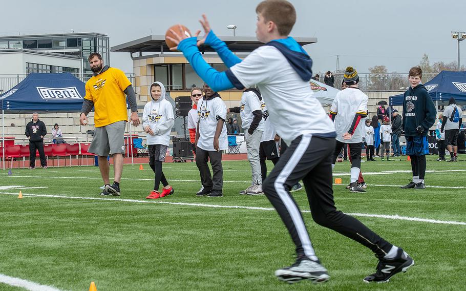 Lucas Hollenbeck, 12, receives a pass from Pittsburg Steelers offensive lineman Alejandro Villanueva during a pro camp at Kaiserslautern High School football field Saturday, April 13, 2019. More than 200 kids from around Germany attended the two-day football camp.
