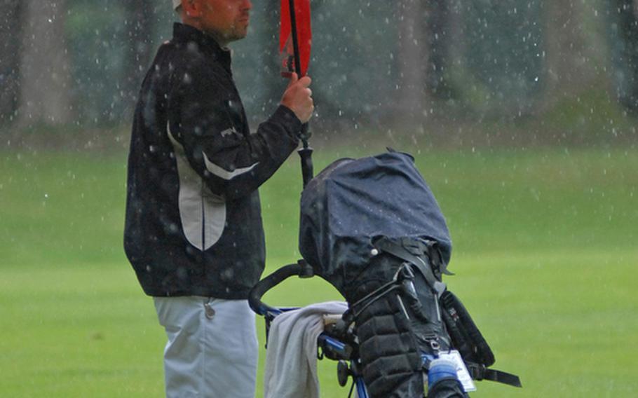Jason Perry, an Air Force master sergeant from Ramstein, tries to stay dry during one of the many downpours during Thursday&#39;s final round of golf for the U.S. Air Forces in Europe golf championships in Ramstein, Germany.