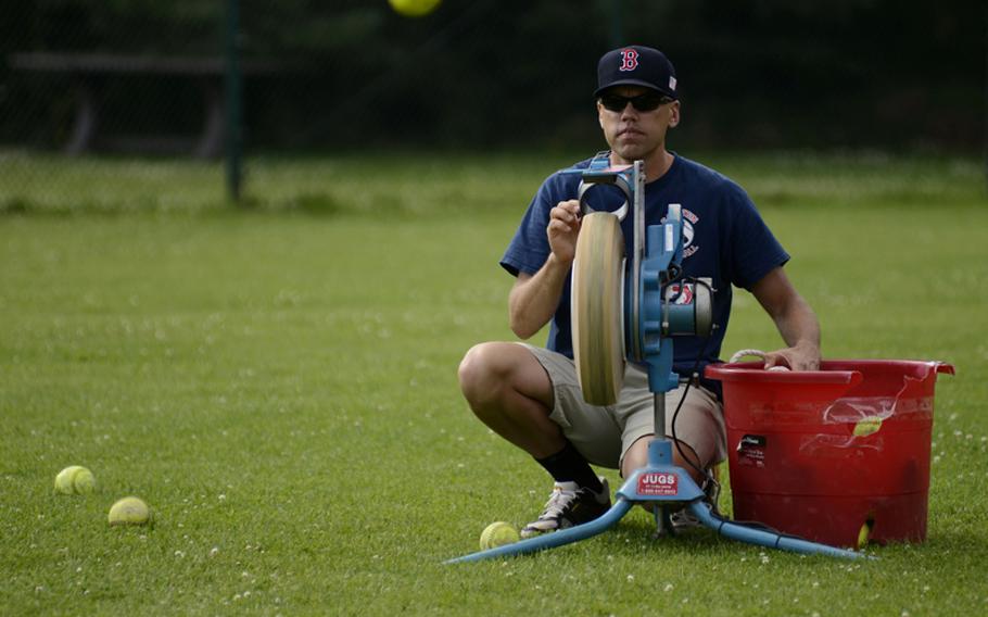 Christian Price, head coach of the Kaiserslautern Military Community 11-12 year-old softball All-Stars, loads softballs into a pitching machine during batting drills July 6, 2012, at Ramstein Air Base, Germany, as the team prepares for the European Little League Regionals at Caronno Pertusella, Italy.