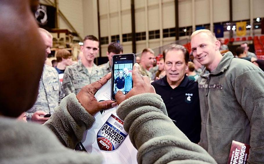 Michigan State's head coach Tom Izzo poses with a servicemember Nov. 9, 2012, after his team was upset by Connecticut 66-62 in the Armed Forces Classic at Ramstein Air Base, Germany.