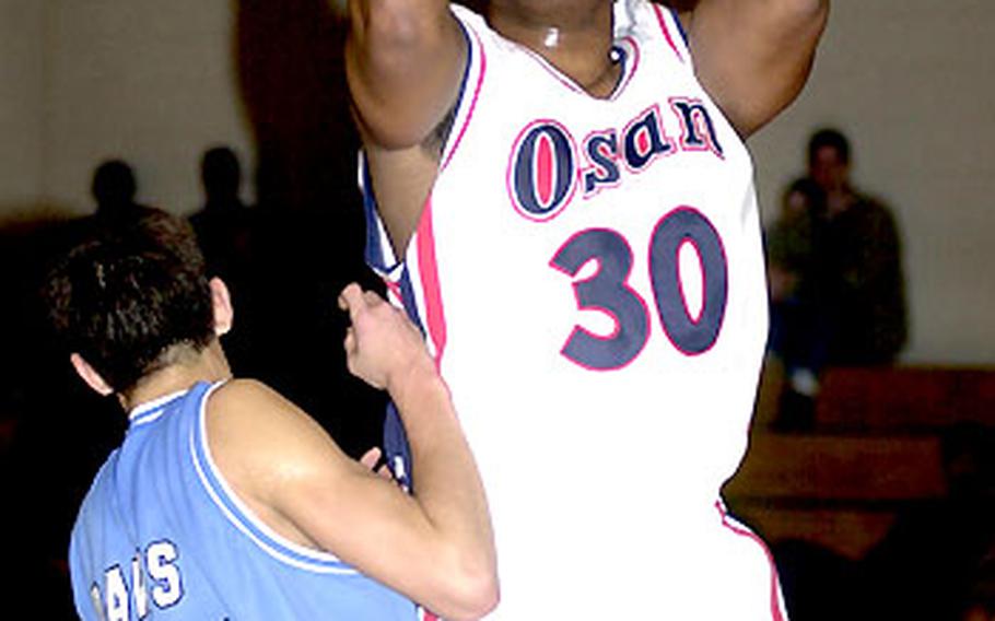 Dwayne Huff of the Osan Defenders puts up a shot over junior center Steve Davis of Osan American High. The Defenders won 88-64, with Huff scoring 14 points. Davis had 12.