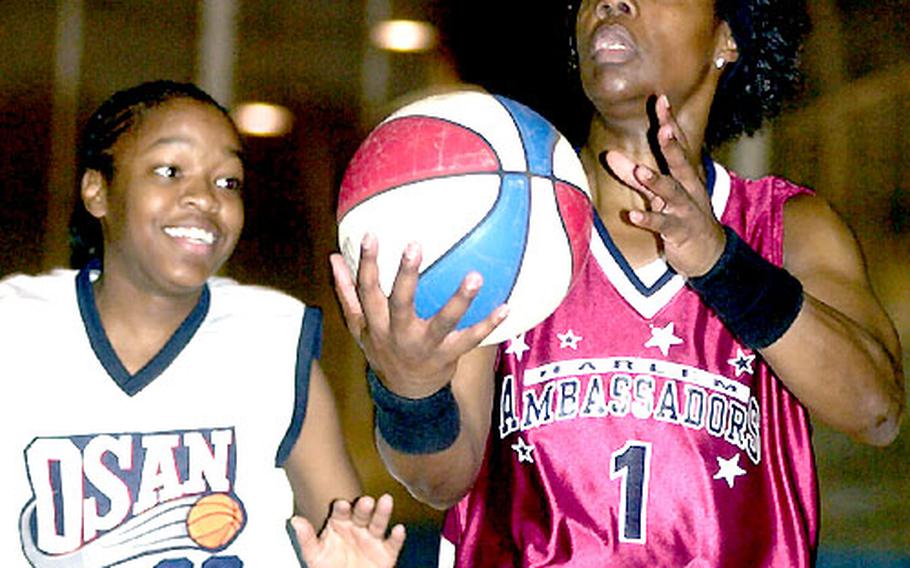 Lade Majic of the Harlem Ambassadors, right, drives against Myisha Hudson of the Osan Defenders during Wednesday’s exhibition at the Osan Sports & Fitness Center.