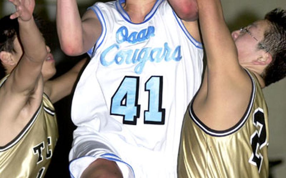 Sophomore Jon Piekarczyk of the Osan American Cougars pulls up for a shot between Taejon Christian International Dragons defenders during Wednesday&#39;s Korean-American Interscholastic Activities Conference boys basketball game at the Cougar Palace, Osan Air Base, South Korea. The Cougars won, 67-31, with Piekarczyk scoring 13 points.