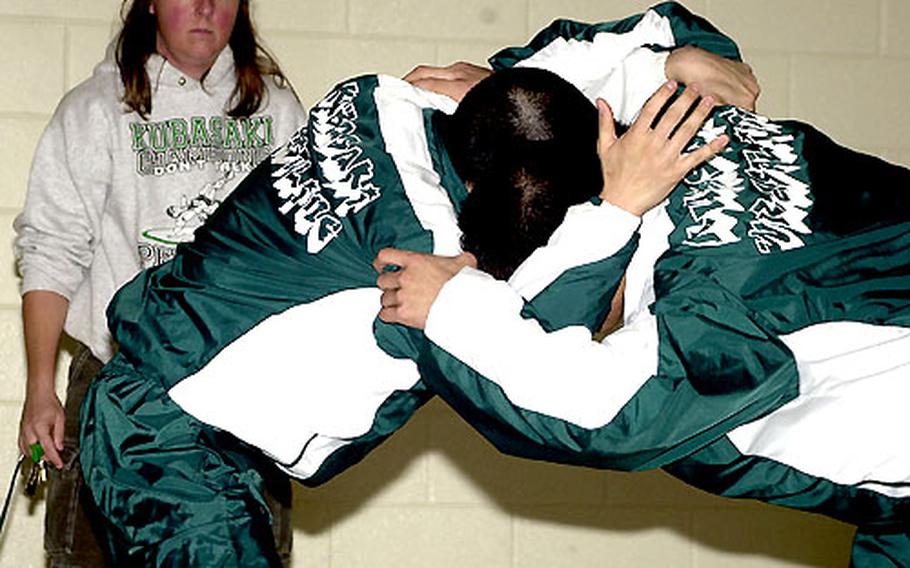 Terry Chumley, Kubasaki Dragons wrestling coach, watches senior wrestlers Wyatt Minei and Will Appling go through their paces during warmups for Saturday's Kubasaki Open wrestling tournament.