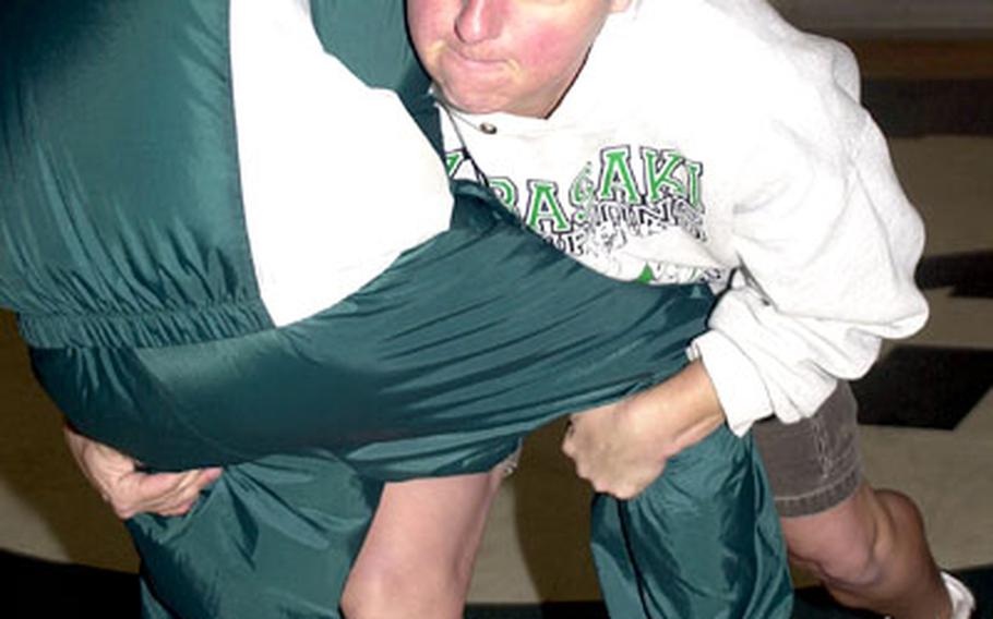 Terry Chumley, Kubasaki Dragons wrestling coach, demonstrates a lift-and-drag technique to 115-pound senior wrestler Wyatt Minei.
