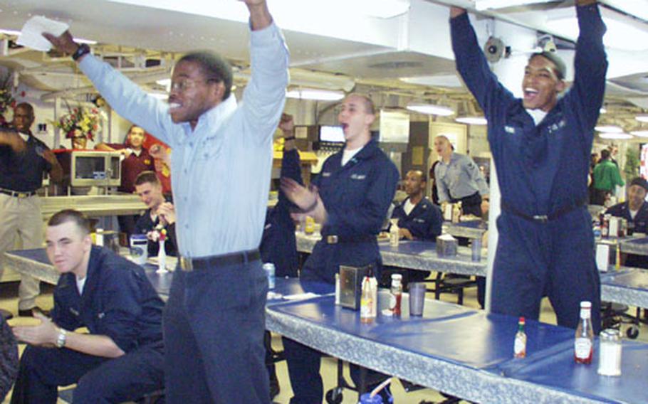 Airman Maurice Reid, left, and Airman Albert Crews celebrate early Monday morning in the mess decks aboard the USS Harry S. Truman as Tampa Bay wins the Super Bowl.