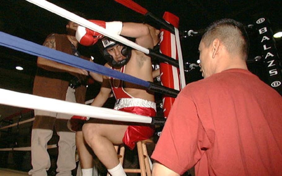 Army Spc. Robert Flores, seated in his corner between rounds at last month's debut of the Army boxing program for lower South Korea. At his left is boxing coach Miguel Marquez.