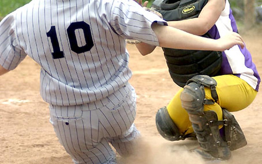 Bitburg's Kristal Stapleton is tagged out at home plate by Mannheim's Salome Martinez during a Saturday softball game in Mannheim, Germany. Bitburg swept the doubleheader, 15-4 and 12-2.