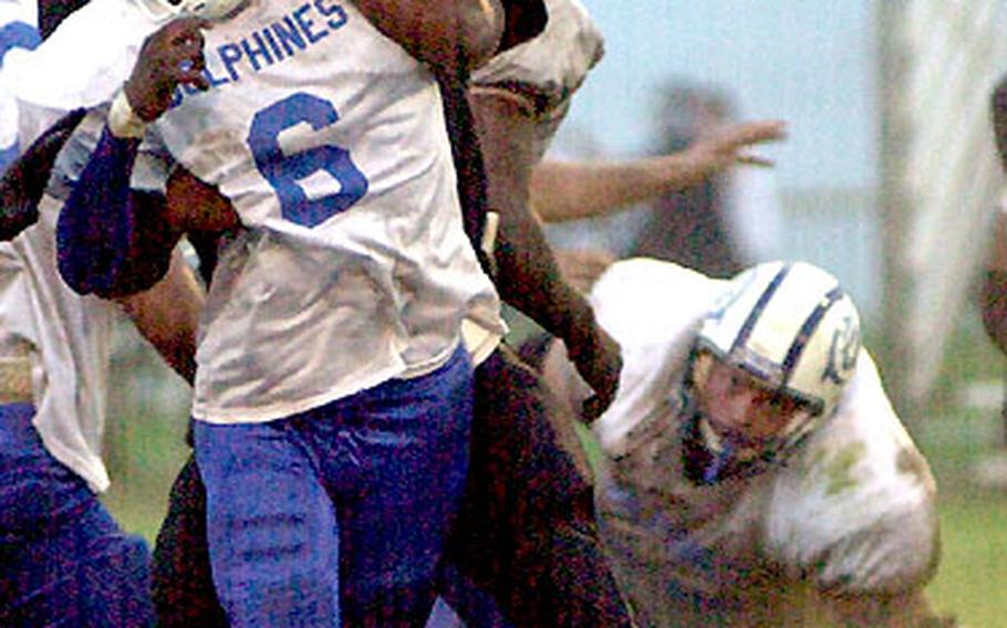 Atsugi White Dolphins quarterback Broderick Johnson is wrapped up by Yokosuka Seahawks defensive lineman Derrick Clay just as he throws the ball during Saturday&#39;s game.