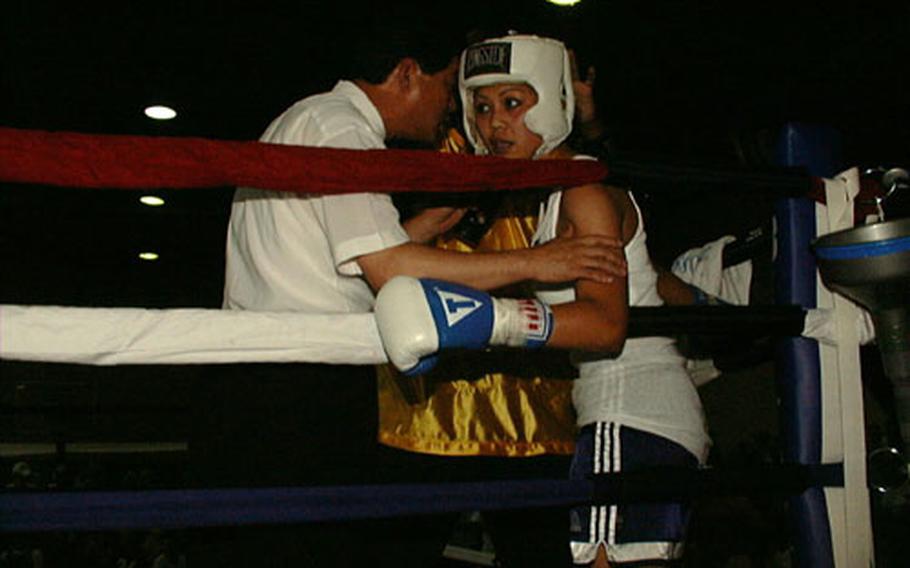 The referee checks the condition of Sgt. Cynthia Nava of 168th Medical Battalion during her bout with Sgt. Camille Adams of 169th Signal Company. Both were on a nine-bout July 4th holiday boxing card put on by Army at Camp Walker in Taegu, South Korea.