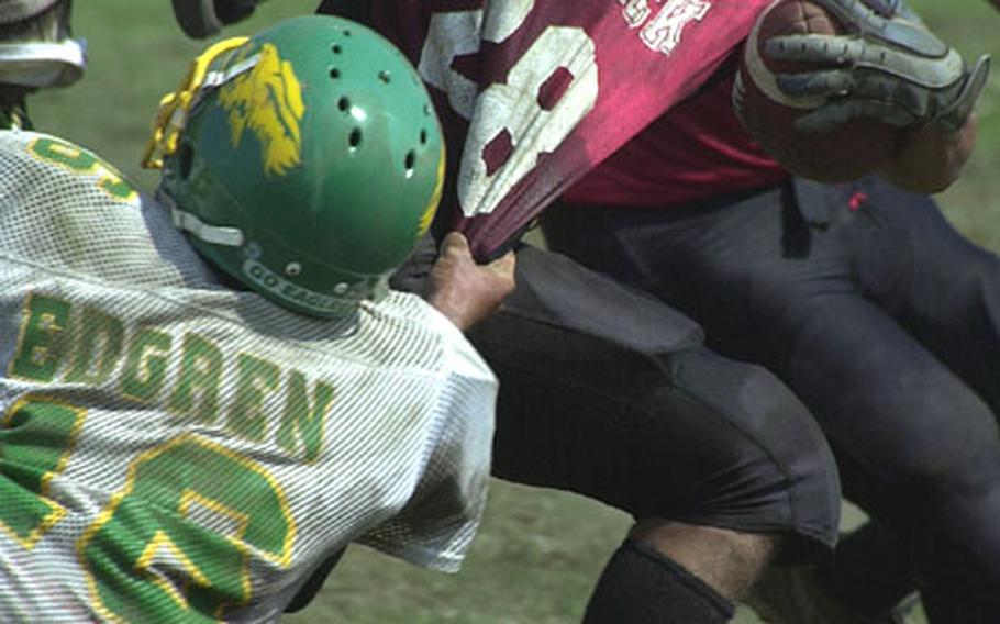 Nile C. Kinnick Red Devils senior tailback Richie Korth (28) has a handful of his jersey grabbed by Robert D. Edgren Eagles free safety Bryan Krueger (16) during Saturday's Japan Football League game at Berkey Field, Yokosuka Naval Base, Japan. Korth ran 20 times for 213 yards and two touchdowns for a Red Devils offense that piled up 492 yards on 47 carries in a 47-6 rout of the Eagles.