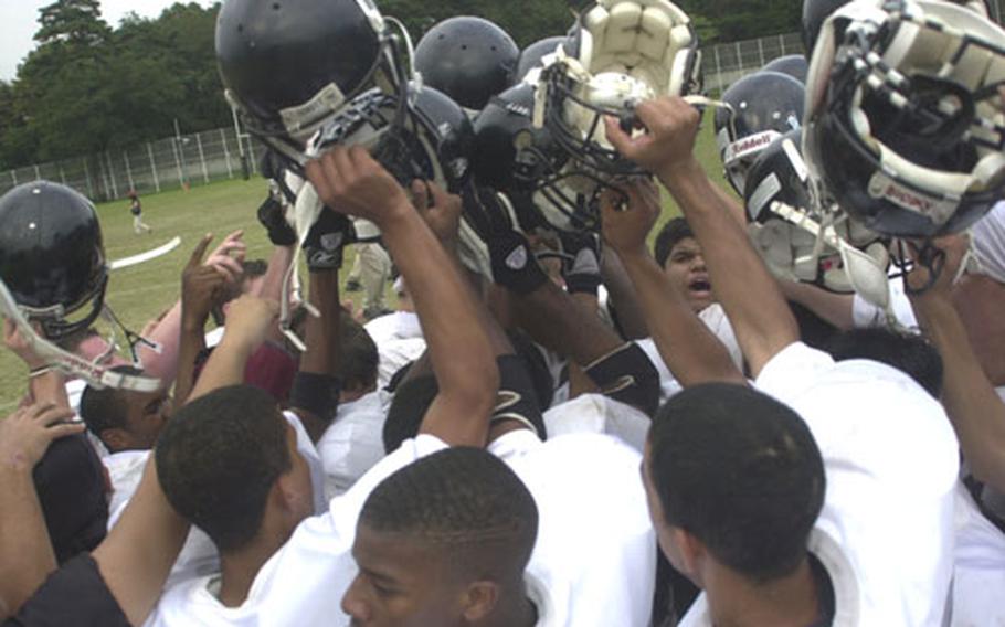 Zama American Trojans players raise their helmets during a celebration after their 48-0 Kanto Plain Association of Secondary Schools victory over American School In Japan at Mustang Valley, Tokyo.