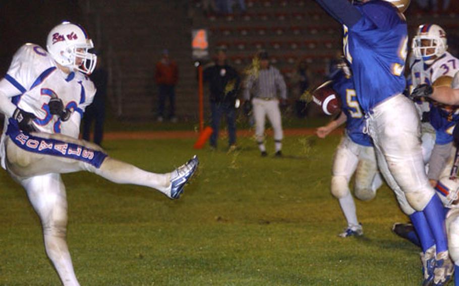 Punting from the back of his own end zone, Ramstein punter Austin Izzo, left, narrowly gets the kick past a leaping Scott Pangrazzi of Wiesbaden in the fourth quarter of the DODDS Division I Football Championship game in Baumholder, Germany, on Saturday.