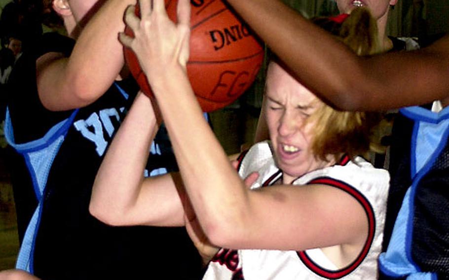 Okinawa Queens center Amanda Dotson grimaces as she comes down with the ball between Yongsan Lady Rebels defenders during Monday's women's championship game.