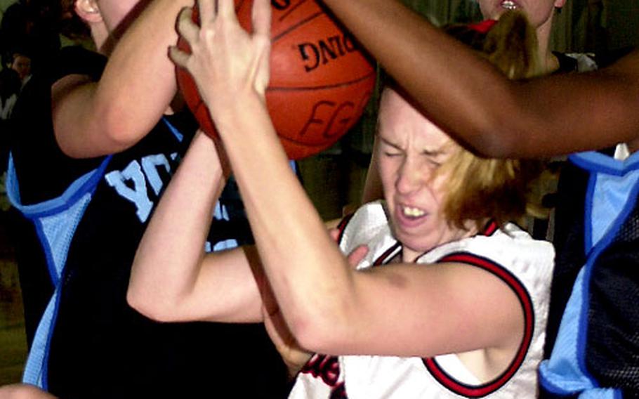 Okinawa Queens center Amanda Dotson grimaces as she comes down with the ball between Yongsan Lady Rebels defenders during Monday&#39;s women&#39;s championship game.