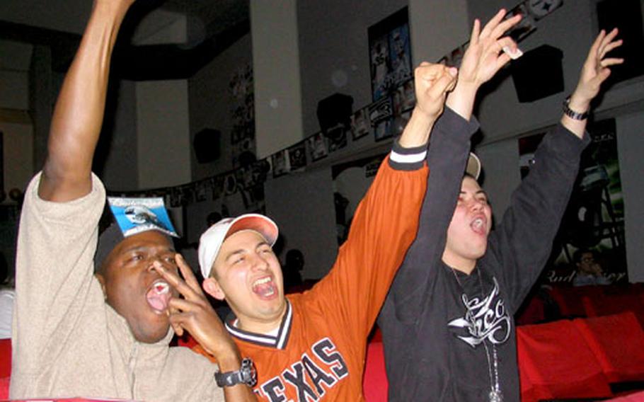 From left, Petty Officer 2nd Class John West, Petty Officer 2nd Class Carlos Aguina and Seaman Apprentice Keith Billet cheer during Super Bowl at Sasebo Naval Base’s Showboat Theater.