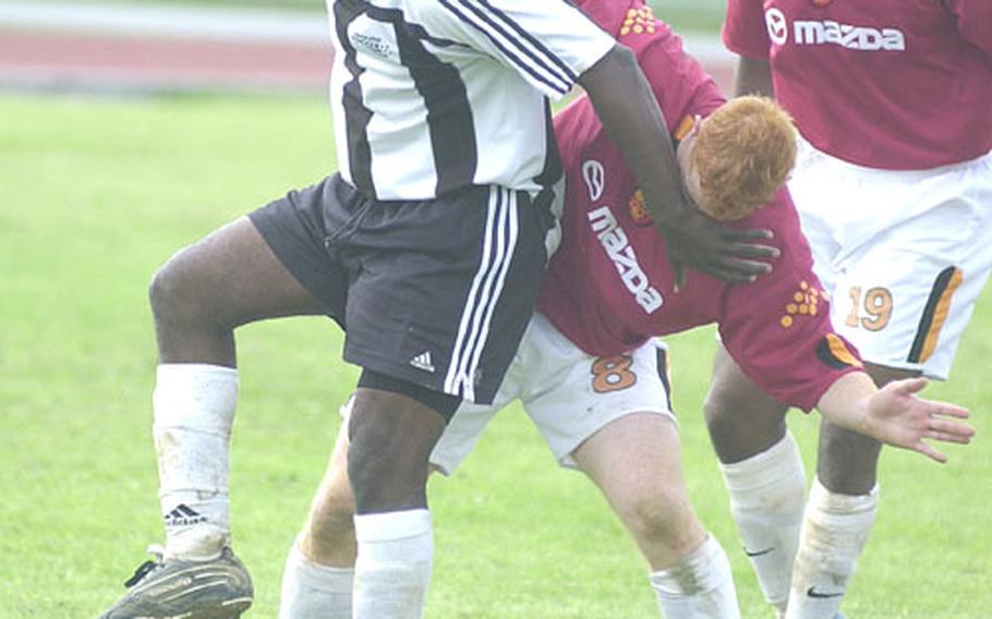 Terence Smith, left, of Iwakuni Marine Corps Air Station, Japan, gets his boot on the ball and his left hand in the face of FC Tafari&#39;s Vincent Casey during Sunday&#39;s championship match of the 2004 Kadena Kup Soccer Tournament at McDonald Stadium, Kadena Air Base, Okinawa.