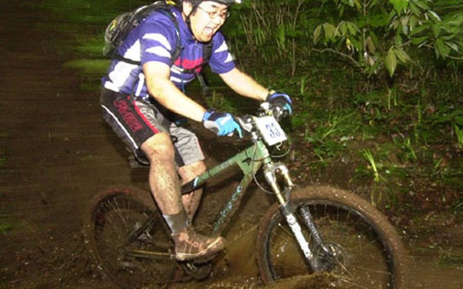 Nobuhisa Okoda enjoying the Tour de Tama as he gets muddy riding through a mud puddle.