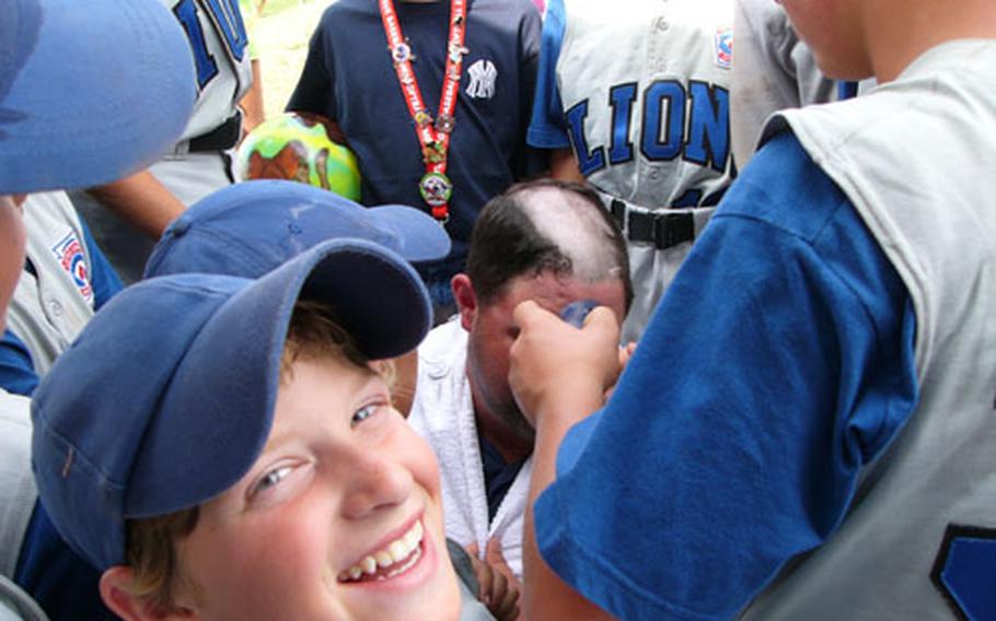 Netherlands third baseman Sam Phillips clearly savors watching Tyler Broome, with clippers, take a swath of hair from the scalp of his coach and father, Andy Broome, on Monday at the Little League picnic pavilion at Kutno, Poland. The elder Broome, along with fellow Brunssum-Schinnen coaches Marc Gratton and George Truini, agreed to let the players shave their heads if the team won its Transatlantic Regional game Sunday against the Italy champions from the Naples military community.