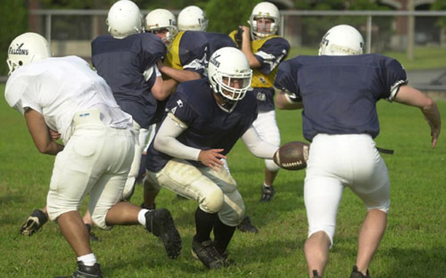 Junior quarterback Bruce Voelker of the Seoul American Falcons hands off during practice Monday at Yongsan Garrison, South Korea.