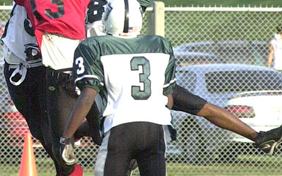 Kadena Buccaneers receiver Gary Wright (13) reaches in vain for a pass between Kubasaki Samurai defenders as Samurai Lenard White (3) watches during Friday&#39;s game. Wright caught a 24-yard touchdown pass and intercepted two passes as the Buccaneers won 24-14.