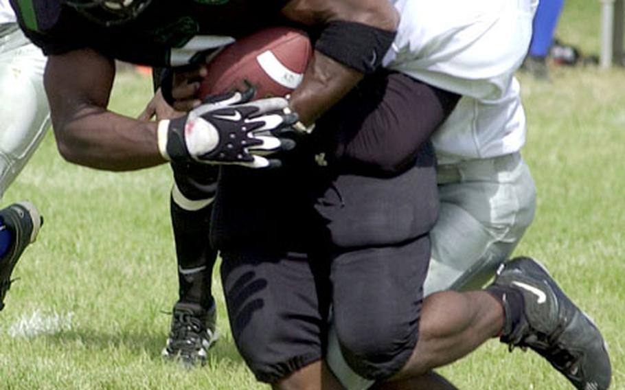 Kadena Dragons running back Trent Beavers is tackled by Darryl Davis of the Schwab Panthers during Saturday&#39;s game at Camp Courtney. Beavers ran 13 times for 156 yards and four touchdowns as the Dragons routed the Panthers 50-7.