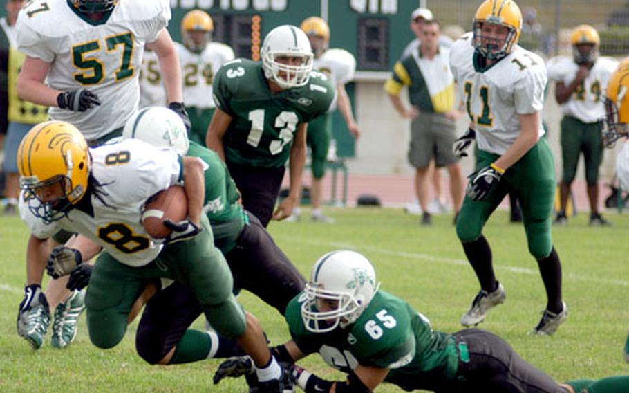 SHAPE sophomore A. J. Rodgers is taken down by a pair of Naples defenders, including senior Matt Briegel, 65, early in the first quarter of SHAPE&#39;s 21-7 win at Naples.