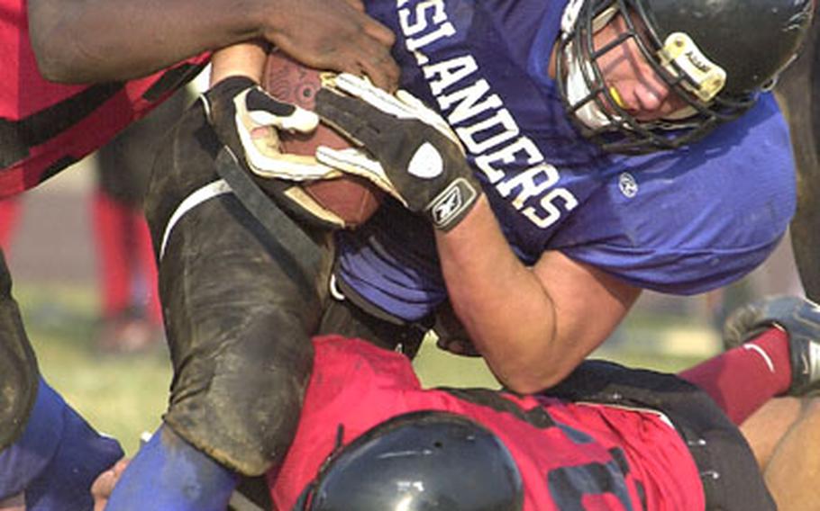 Islanders fullback Ted Awana barrels his way between Buccaneers defenders Gary Wright, top, and Alex Weaver.