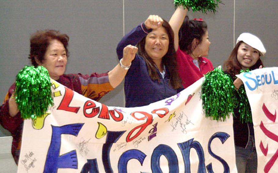 Keiko Bradford, middle right, and some of her friends and relatives hold up a banner supporting the Seoul American Falcons during Tuesday&#39;s play in the Class AA tournament at Kubasaki. Bradford, who lives at Yongsan Garrison and hails from Naha, Okinawa, was cheering on her daughter, Falcons sophomore Lorna Haney.