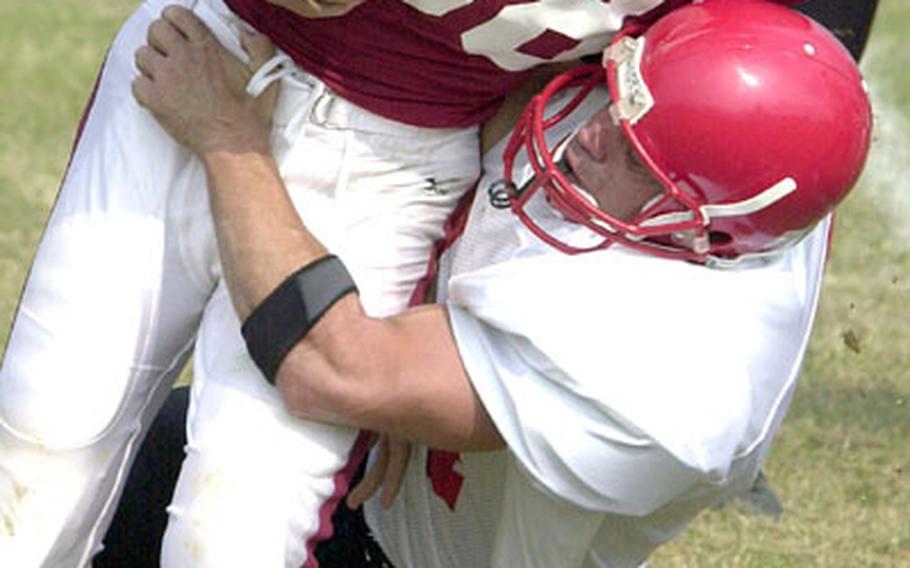 Ryukyu University Stingray running back Tetsuo Goya (88) gets wrapped up by Foster-Futenma Bulldogs defender Mark Scheffer during Sunday&#39;s Okinawa Football League game. The Bulldogs amassed nine touchdowns and 591 yards on offense and held the Stingray to 33 yards and one first down in a 64-0 rout, three days after being forced to forfeit their five victories for having used an ineligible player.