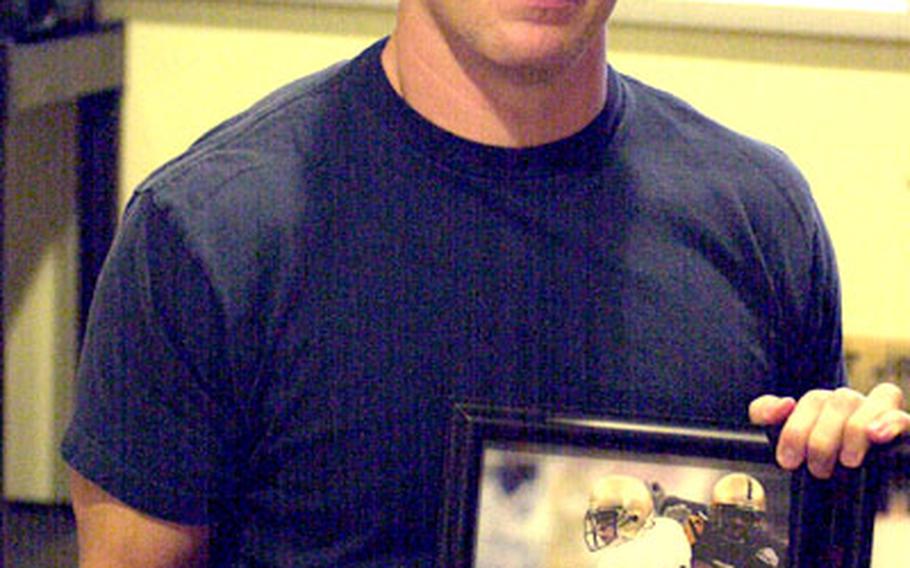 Scott Jones, Naval Academy Class of 2000 and a reserve quarterback/receiver for four seasons at Annapolis, displays mementos of his years in Midshipmen uniform. The Marine Corps first lieutenant is assigned as an Air Defense Controller at Futenma Marine Corps Air Station on Okinawa and lives with his wife, Kim, at Kadena Air Base, Okinawa.