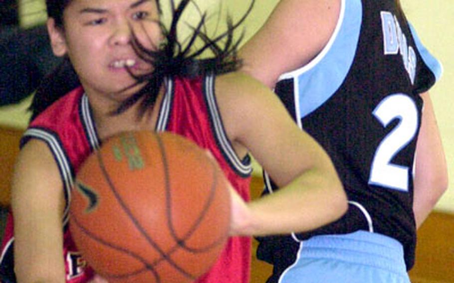 E.J. King guard Bianca Cruz passes the ball past Mina Davis of Osan American during Wednesday&#39;s round-robin play in the Class A (small schools) tournament. Osan won 69-47.